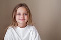 Pretty little girl blue eyes and long blonde hair wears white shirt isolated beige background. Caucasian beautiful Royalty Free Stock Photo