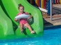 A beautiful little girl is riding a water slide in the water park Royalty Free Stock Photo