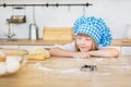 Pretty little girl in a cook looks on a dough on a table