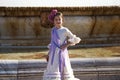 a pretty little girl dancing flamenco dressed in a beige dress with ruffles and purple fringes in a famous square in seville, Royalty Free Stock Photo