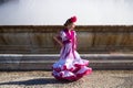 A pretty little girl dancing flamenco dressed in a white dress with pink frills and fringes in a famous square in seville, spain. Royalty Free Stock Photo