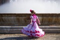 A pretty little girl dancing flamenco dressed in a white dress with pink frills and fringes in a famous square in seville, spain. Royalty Free Stock Photo