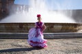 A pretty little girl dancing flamenco dressed in a white dress with pink frills and fringes in a famous square in seville, spain. Royalty Free Stock Photo