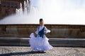 A pretty little girl dancing flamenco dressed in a white dress with ruffles and blue fringes in a famous square in seville, spain Royalty Free Stock Photo