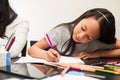 Pretty little girl doing homework near her mother on the black table at home. Little latin girl use pink pencil to write on the Royalty Free Stock Photo