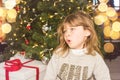 pretty little girl in a dress waiting at the foot of the Christmas tree for the opening of presents Royalty Free Stock Photo