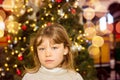 pretty little girl in a dress waiting at the foot of the Christmas tree for the opening of presents Royalty Free Stock Photo