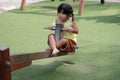 Pretty little girl dressed in Thai on outdoor seesaw in playground