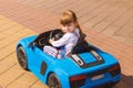 A Pretty Little Girl Is Driving A Battery-Powered Car In An Amusement Park. A happy child is sitting in his blue toy car. The conc Royalty Free Stock Photo