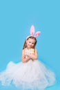 Pretty little girl easter bunny sitting on blue background