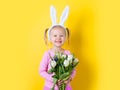 Pretty little girl easter bunny with spring flower on yellow background Royalty Free Stock Photo