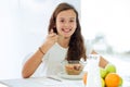 Pretty little girl eating cereals and smiling at the camera on kitchen at home Royalty Free Stock Photo
