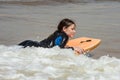 pretty little girl enjoying surfing the waves with a bodyboard during her vacation