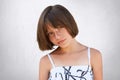 Pretty little girl with freckles, dark eyes and short hairstyle wearing summer white dress posing against white background having