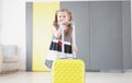 Pretty little girl going on vacation, packed stuff in yellow suitcase, kid in lovely summer dress