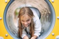 Pretty, little girl, having fun, crawling on pipe on children playground.