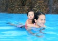 Pretty little girl with her mother playing in swimming pool outdoors Royalty Free Stock Photo