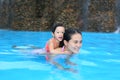 Pretty little girl with her mother playing in swimming pool outdoors Royalty Free Stock Photo