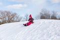 Pretty little girl in her ski suit screaming of joy while sliding down a small snow Royalty Free Stock Photo