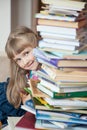 Pretty little girl hiding behind a stack of books