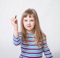 Pretty little girl holding a black felt-tip pen and drawing some Royalty Free Stock Photo