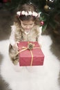 A pretty little girl kid holds a big Christmas gift in front of a Christmas tree. Christmas concept, background Royalty Free Stock Photo