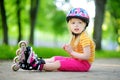 Pretty little girl learning to roller skate on beautiful summer day in a park Royalty Free Stock Photo