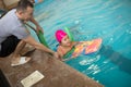 Pretty little girl learning to swim in the pool with swim coach trainer