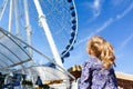 Pretty little girl looks at ferris wheel against a blue sky Royalty Free Stock Photo