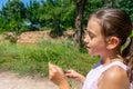 Pretty little girl with a mask to protect herself from the coronavirus picking a flower on a path surrounded by nature