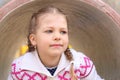 Pretty little girl peeks up of pipe on playground