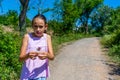 Pretty little girl picking a flower on a path surrounded by nature