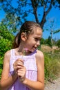 Pretty little girl picking a flower on a path surrounded by nature