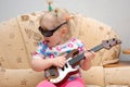 Pretty little girl play on toy guitar. Royalty Free Stock Photo