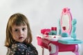 Pretty Little Girl Playing With Cosmetics Near Dressing Table In The Room. 2 Year Old Royalty Free Stock Photo