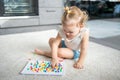 Pretty little girl playing with mushroom nail mosaic at home. Hobby and leisure time Royalty Free Stock Photo