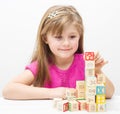 Pretty little girl playing with wooden cubes with letters and numbers