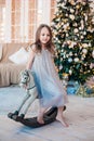 Pretty little girl posing on antique rocking horse against Christmas tree indoors. Royalty Free Stock Photo