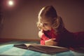 Pretty little girl reading book in her hiding place with flashlight at darkness Royalty Free Stock Photo