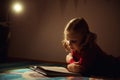 Pretty little girl reading book in her hiding place with flashlight at darkness Royalty Free Stock Photo