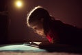 Pretty little girl reading book in her hiding place with flashlight at darkness Royalty Free Stock Photo