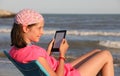 Pretty little girl reads an ebook on the beach Royalty Free Stock Photo