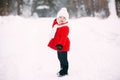 Pretty little girl in red coat in winter forest. Little girl having fun on winter day Royalty Free Stock Photo