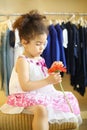 Pretty little girl with red flower sits at pouf in