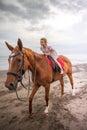 Pretty little girl riding horse on the beach. Happy childhood. Sunset time by the sea. Outdoor activities. Vacation concept. Bali Royalty Free Stock Photo