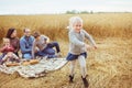 A pretty little girl runs near his family on a field Royalty Free Stock Photo