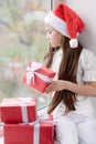 Pretty little girl in Santa hat dreaming by the window holding g Royalty Free Stock Photo