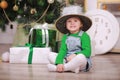 Pretty little girl in shine hat smiling with present near the Christmas tree Royalty Free Stock Photo