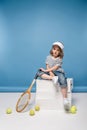 pretty little girl sitting on white boxes and holding tennis raquet Royalty Free Stock Photo