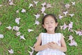 Pretty little girl sleeping on green grass with fall pink flower in the garden outdoor Royalty Free Stock Photo